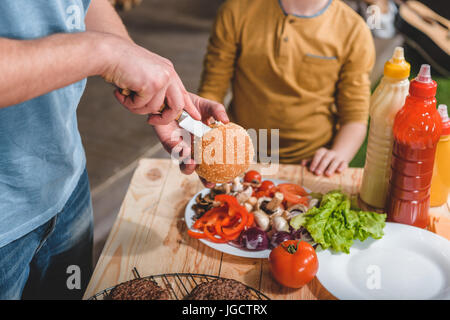 partial view of dad and son cooking meat burgers together Stock Photo