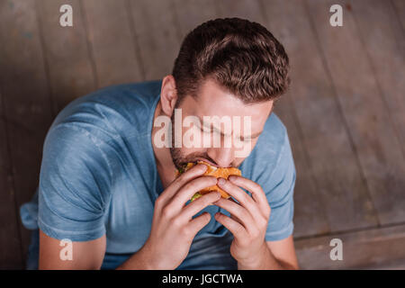 high angle view of young man eating burger Stock Photo