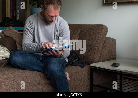 Man sitting on couch using a digital tablet Stock Photo