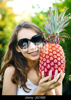 Portrait of a smiling woman with braces holding a pineapple Stock Photo