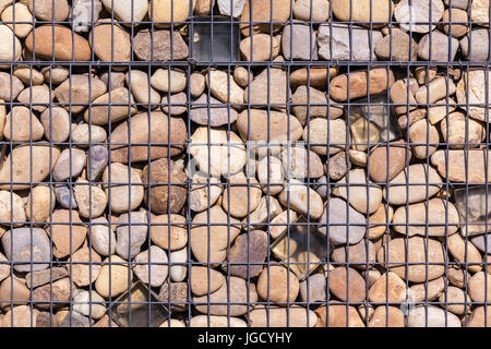 metallic basket net filled by natural stones as a fence Stock Photo