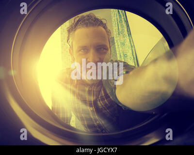 Happy man loading the washing machine, bright sun in the back, golden flat color style Stock Photo