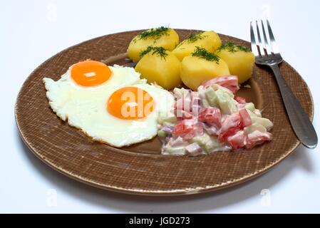 Fried egg with fresh potatoes and tomato cucumber salad. Stock Photo