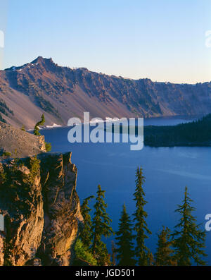 USA, Oregon, Crater Lake National Park, Sunrise on west rim of Crater Lake with Hillman Peak (left) overlooking Wizard Island. Stock Photo