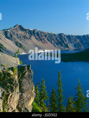 USA, Oregon, Crater Lake National Park, Morning light on west rim of Crater Lake with Hillman Peak (left) overlooking Wizard Island. Stock Photo