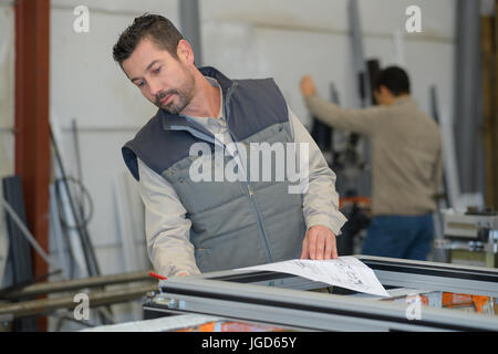 factory worker searching for pvc window profiles on a rack Stock Photo