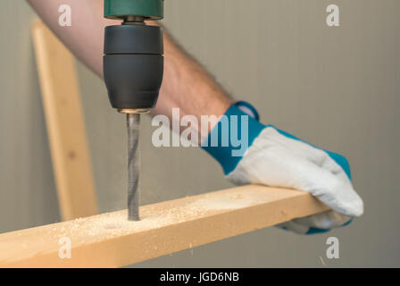 Carpenter handyman using electric drill to make holes on plank on the woodwork workshop table Stock Photo