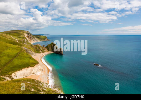 Durdle Door, Dorset touris attraction view from west side. Sunny afternoon light with clouds on blue sky and azure sea.