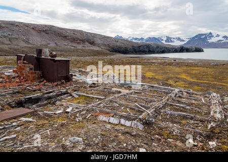 The rusting remains of a stove remain in position above the wooden foundations of an abandoned hut at New London in Spitzbergen Stock Photo