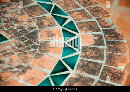A mosaic element on an old table, orange and blue. Stock Photo