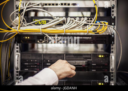 Man's hand connecting cables on modern computer peripheral hardware. Stock Photo