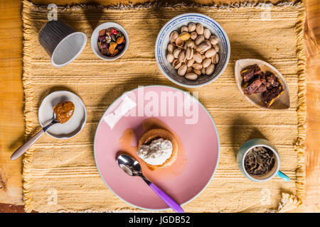 Flan -  creme on top, on a pink plate over a wooden board, served with chocolate cookies, dulce de leche confection , coffee and nuts. Stock Photo