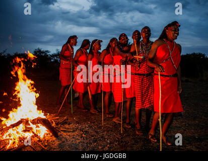 KENYA, MASAI MARA - SEPTEMBER 22, 2015: Warriors the Masai tribe dancing ritual dance around the fire late in the evening. Stock Photo