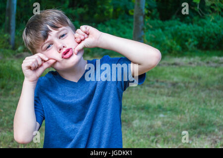 young caucasian boy making funny face outdoors Stock Photo