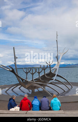 Tourists resting by The Sun Voyager sculpture in Reykjavik Stock Photo