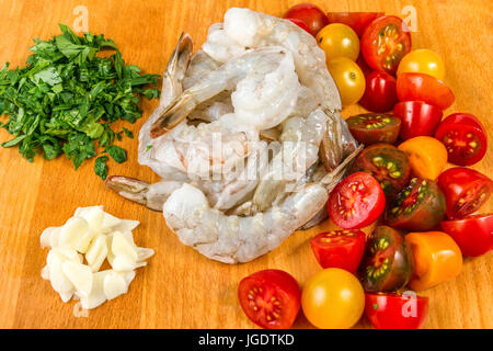 Seafood. Ingridients for spaghetti pasta with prawns or shrimps with mixed colours cherry tomatoes fresh parsley Stock Photo