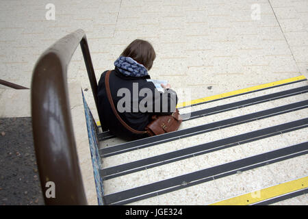 commuter passenger tourist sitting on a step viewed from behind Stock Photo