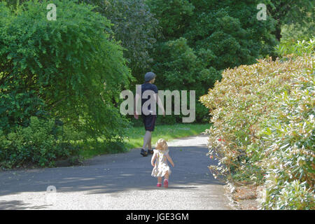 father and daughter toddler baby walking in park mirroring each other along path Stock Photo