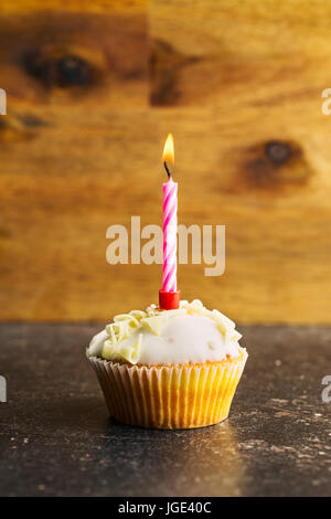 Cupcake with burning candle on table. Stock Photo