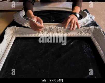 Hands of Caucasian man detailing picture frame Stock Photo