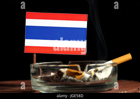 Thai flag with burning cigarette in ashtray isolated on black background Stock Photo