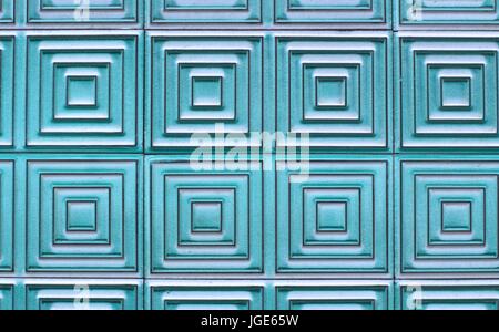 Old tiles on the wall with a unique square pattern, turquoise color. Stock Photo