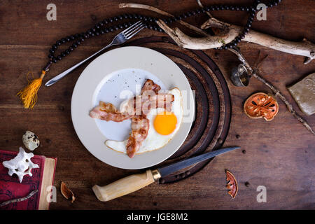 Egg and bacon served on a plate, english breakfast on wooden table. Boutique hotel style. Top view. Stock Photo