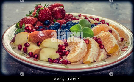 A closeup view of a platter of mixed fruits including strawberries, oranges, blueberries, apples and bananas Stock Photo