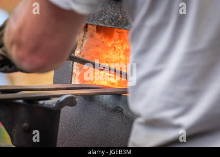 A blacksmith inserting steel rods into the hot oven  during medieval fair festival in Streatham Park in London Stock Photo