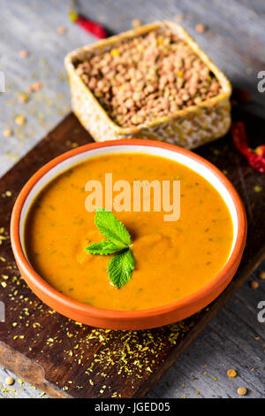 closeup of an earthenware bowl with lentil and quinoa puree on a rustic wooden table Stock Photo
