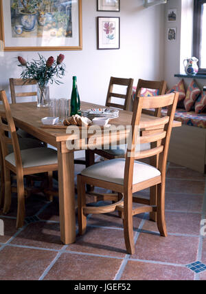 Wooden diningroom table and chairs on terracotta tiled floor. Stock Photo