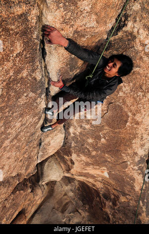 Young south asian woman rock climbs in the desert on a very difficult wall Stock Photo