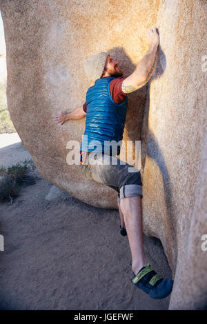 Young caucasian man with beard rock climbs in the desert with no safety equipment Stock Photo