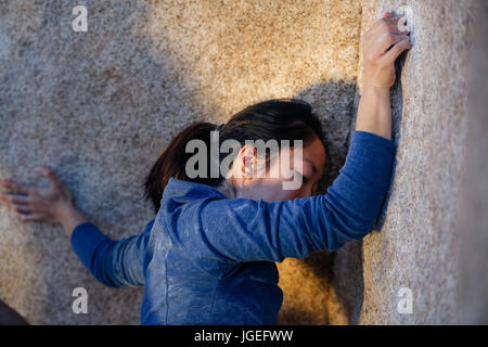 Young asian woman rock climbs in the desert with no safety equipment Stock Photo