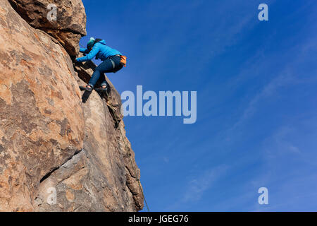 Young mixed race woman rock climbs in the desert with large copy space along right side Stock Photo