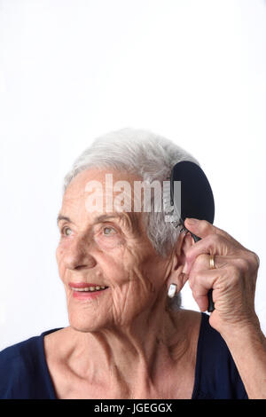 Senior woman combing her hair on white background Stock Photo
