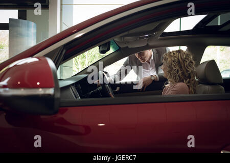 Salesman assisting female customer sitting in car Stock Photo