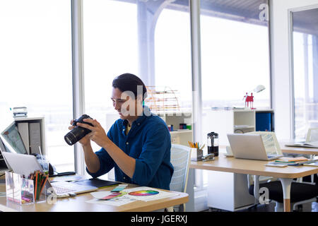 Male executive reviewing captured photograph at his desk in office Stock Photo