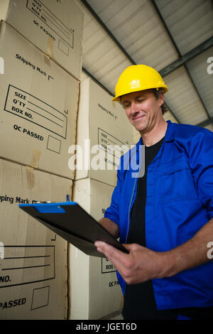 Smiling worker writing on clipboard in olives factory Stock Photo