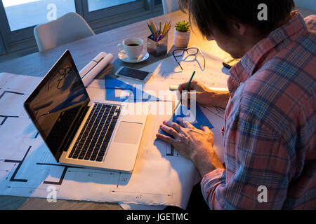 Male architect working on blueprint at his desk in office Stock Photo