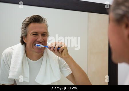 Mature man brushing his teeth in bathroom Stock Photo
