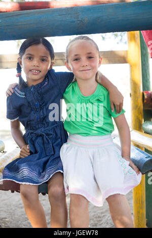 Portrait of smiling girls sitting on jungle gym at playground Stock Photo