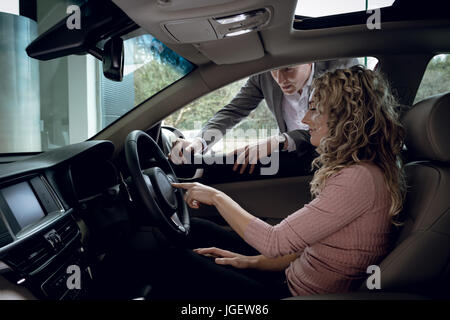Salesman explaining to customer sitting in car Stock Photo