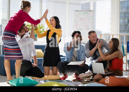 Business colleagues giving high five to each other in the office Stock Photo