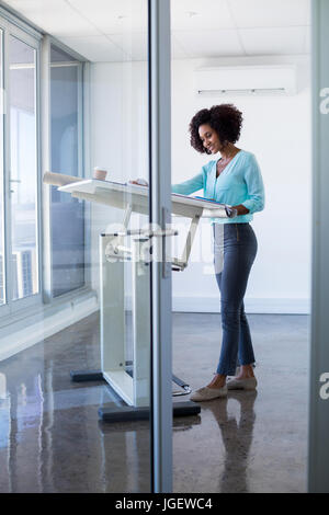Female architect working on blueprint over drafting table in office Stock Photo