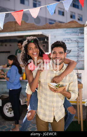 Portrait of smiling man giving piggy back to woman Stock Photo