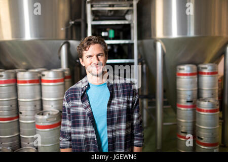 Portrait of smiling male worker standing by storage tanks at factory Stock Photo