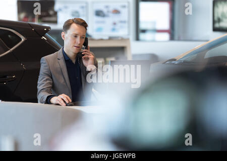 Car salesperson talking on landline phone Stock Photo