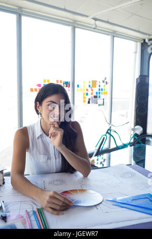 Female architect working on blueprint at her desk in office Stock Photo