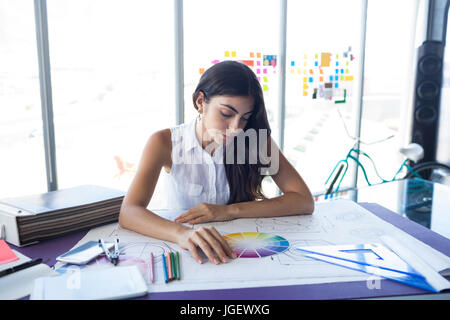 Female architect working on blueprint at her desk in office Stock Photo